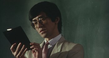 Movie still from “School in the Crosshairs” (1981), directed by Nobuhiko Ôbayashi – A man in a suit and tie holding a cell phone to his ear; Close Up shot, Low angle