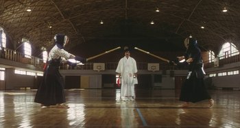 Movie still from “School in the Crosshairs” (1981), directed by Nobuhiko Ôbayashi – A man standing in front of two other men holding swords; Wide shot, Low angle