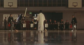 Movie still from “School in the Crosshairs” (1981), directed by Nobuhiko Ôbayashi – A group of people sitting in a room; Extreme Wide shot, Low angle