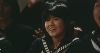 Movie still from “School in the Crosshairs” (1981), directed by Nobuhiko Ôbayashi – A young woman wearing a sailor suit smiling for the camera; Close Up shot, High angle