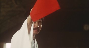 Movie still from “School in the Crosshairs” (1981), directed by Nobuhiko Ôbayashi – A man holding a red flag up in the air; Close Up shot, Low angle