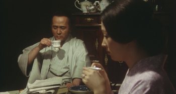 Movie still from “School in the Crosshairs” (1981), directed by Nobuhiko Ôbayashi – A man and a woman sitting at a table drinking tea; Medium shot, Over the shoulder angle