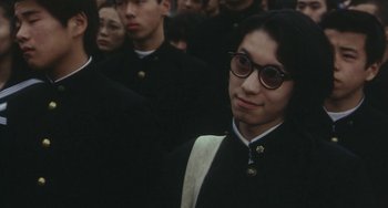 Movie still from “School in the Crosshairs” (1981), directed by Nobuhiko Ôbayashi – A group of people standing around each other wearing glasses; Close Up shot, High angle