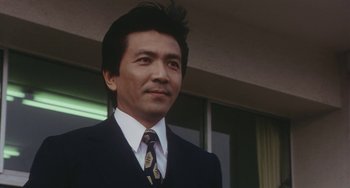 Movie still from “School in the Crosshairs” (1981), directed by Nobuhiko Ôbayashi – A person wearing a suit and tie; Close Up shot, Low angle
