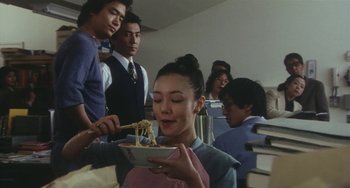 Movie still from “School in the Crosshairs” (1981), directed by Nobuhiko Ôbayashi – A group of people standing around a bowl of noodles; Medium shot, Low angle