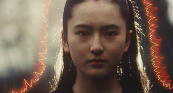 Movie still from “School in the Crosshairs” (1981), directed by Nobuhiko Ôbayashi – A woman with long black hair is looking at the camera; Close Up shot, Low angle