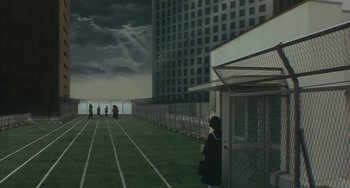 Movie still from “School in the Crosshairs” (1981), directed by Nobuhiko Ôbayashi – A person standing on a track in front of a building; Extreme Wide shot, High angle