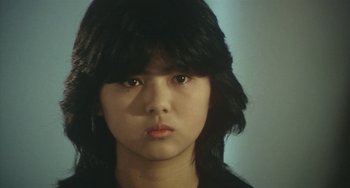 Movie still from “School in the Crosshairs” (1981), directed by Nobuhiko Ôbayashi – A young woman with long black hair looking at the camera; Close Up shot, High angle