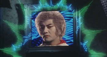 Movie still from “School in the Crosshairs” (1981), directed by Nobuhiko Ôbayashi – A picture of a man in front of an image of an electric wave; Medium shot, Low angle