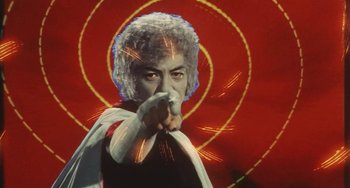 Movie still from “School in the Crosshairs” (1981), directed by Nobuhiko Ôbayashi – An older man is pointing to the camera with his finger; Medium shot, Low angle