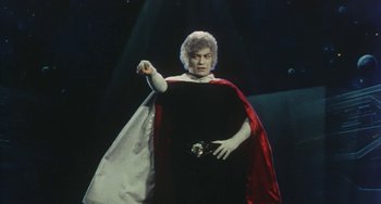 Movie still from “School in the Crosshairs” (1981), directed by Nobuhiko Ôbayashi – A man dressed in a black and red cape and holding a sword in his right hand; Medium shot, Low angle