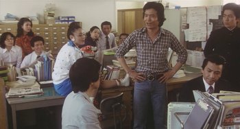 Movie still from “School in the Crosshairs” (1981), directed by Nobuhiko Ôbayashi – A group of people standing around a room; Medium shot, Over the shoulder angle