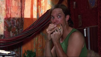 Movie still from “Scooby-Doo” (2002), directed by Raja Gosnell – A man eating a sandwich in a room; Medium shot, Low angle