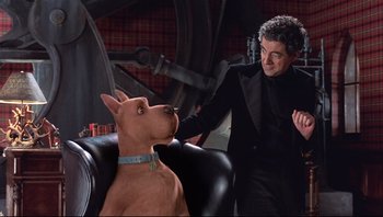 Movie still from “Scooby-Doo” (2002), directed by Raja Gosnell – A man standing next to a dog in a room; Medium shot, Over the shoulder angle