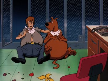 Movie still from “Scooby-Doo on Zombie Island” (1998), directed by Jim Stenstrum – A couple of people sitting next to each other on the ground; Medium shot, High angle