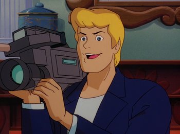 Movie still from “Scooby-Doo on Zombie Island” (1998), directed by Jim Stenstrum – A man holding a video camera while wearing a suit and tie; Close Up shot, Low angle