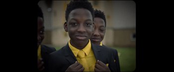 Movie still from “Scrapper” (2023), directed by Charlotte Regan – Two young men in suits and ties posing for a picture; Close Up shot, Low angle