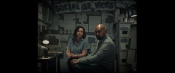 Movie still from “Scrapper” (2023), directed by Charlotte Regan – A man and a woman sitting next to each other in a room; Medium shot, Over the shoulder angle