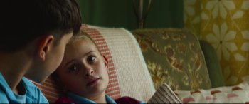 Movie still from “Scrapper” (2023), directed by Charlotte Regan – A young boy sitting on a couch with his mother; Close Up shot, Over the shoulder angle