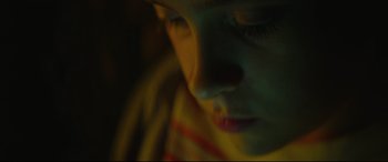 Movie still from “Scrapper” (2023), directed by Charlotte Regan – A woman's face in the dark; Extreme Close Up shot, Overhead angle