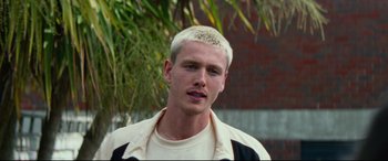 Movie still from “Scrapper” (2023), directed by Charlotte Regan – A man with a white hair and a white shirt; Close Up shot, Low angle