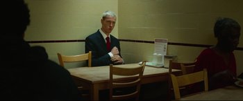 Movie still from “Scrapper” (2023), directed by Charlotte Regan – A man sitting at a table in a restaurant; Medium shot, Over the shoulder angle