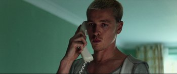 Movie still from “Scrapper” (2023), directed by Charlotte Regan – A man holding a phone up to his ear; Close Up shot, Low angle