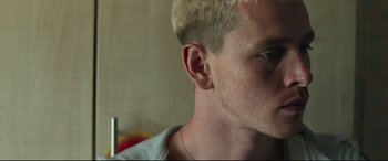 Movie still from “Scrapper” (2023), directed by Charlotte Regan – A person's face with a white hair; Close Up shot, Low angle