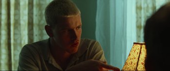 Movie still from “Scrapper” (2023), directed by Charlotte Regan – A man with a shaved head is sitting in a room; Close Up shot, Low angle