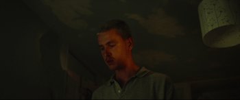 Movie still from “Scrapper” (2023), directed by Charlotte Regan – A young man is standing in the dark; Close Up shot, Low angle