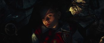 Movie still from “Scrapper” (2023), directed by Charlotte Regan – A young boy is sitting in the dark; Close Up shot, High angle