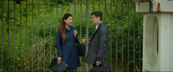 Movie still from “Scrapper” (2023), directed by Charlotte Regan – A man and a woman standing next to each other holding suitcases; Wide shot, Over the shoulder angle