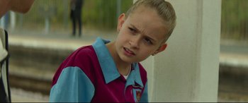 Movie still from “Scrapper” (2023), directed by Charlotte Regan – A young girl with a sad look on her face; Close Up shot, Over the shoulder angle