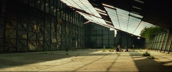 Movie still from “Scrapper” (2023), directed by Charlotte Regan – An abandoned building with a person sitting in it; Extreme Wide shot, Low angle