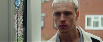 Movie still from “Scrapper” (2023), directed by Charlotte Regan – A person wearing a white shirt; Close Up shot, Low angle