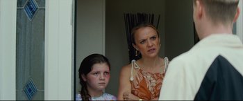 Movie still from “Scrapper” (2023), directed by Charlotte Regan – A woman standing next to a young girl in front of a door; Close Up shot, Over the shoulder angle