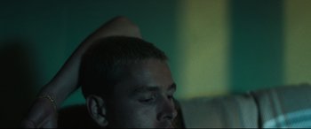 Movie still from “Scrapper” (2023), directed by Charlotte Regan – A man's face in a dark room; Extreme Close Up shot, Low angle