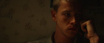 Movie still from “Scrapper” (2023), directed by Charlotte Regan – A person's face in a dark room; Close Up shot, Low angle