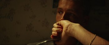 Movie still from “Scrapper” (2023), directed by Charlotte Regan – A man with his hand in his mouth; Extreme Close Up shot, Low angle