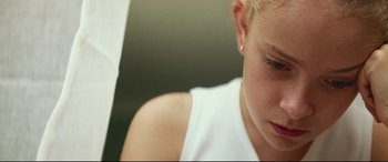 Movie still from “Scrapper” (2023), directed by Charlotte Regan – A person wearing a white t - shirt; Close Up shot, Low angle
