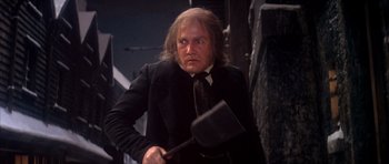 Movie still from “Scrooge” (1970), directed by Ronald Neame – A man in a suit and tie holding a meat spatula; Medium shot, Low angle