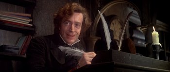 Movie still from “Scrooge” (1970), directed by Ronald Neame – A man holding a feather pen in front of a clock; Close Up shot, High angle