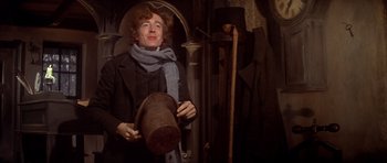 Movie still from “Scrooge” (1970), directed by Ronald Neame – A man holding a hat in a dark room; Medium shot, Low angle