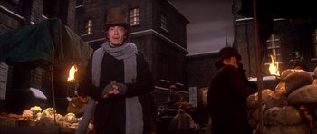 Movie still from “Scrooge” (1970), directed by Ronald Neame – A man in a top hat and scarf holding a cross; Medium shot, Low angle
