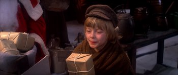 Movie still from “Scrooge” (1970), directed by Ronald Neame – A young boy holding a wrapped package in his hands; Close Up shot, High angle