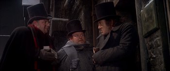 Movie still from “Scrooge” (1970), directed by Ronald Neame – Two men in top hats and coats talking to each other; Medium shot, Low angle