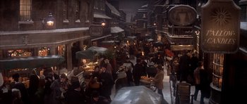 Movie still from “Scrooge” (1970), directed by Ronald Neame – A crowd of people walking down a street at night under an umbrella; Extreme Wide shot, High angle