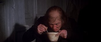 Movie still from “Scrooge” (1970), directed by Ronald Neame – An old woman is holding a bowl with a fork in it; Medium shot, High angle