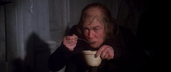 Movie still from “Scrooge” (1970), directed by Ronald Neame – An old man eating something while holding a spoon; Medium shot, High angle