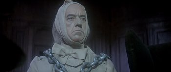 Movie still from “Scrooge” (1970), directed by Ronald Neame – A man with a metal chain around his neck; Close Up shot, Low angle
